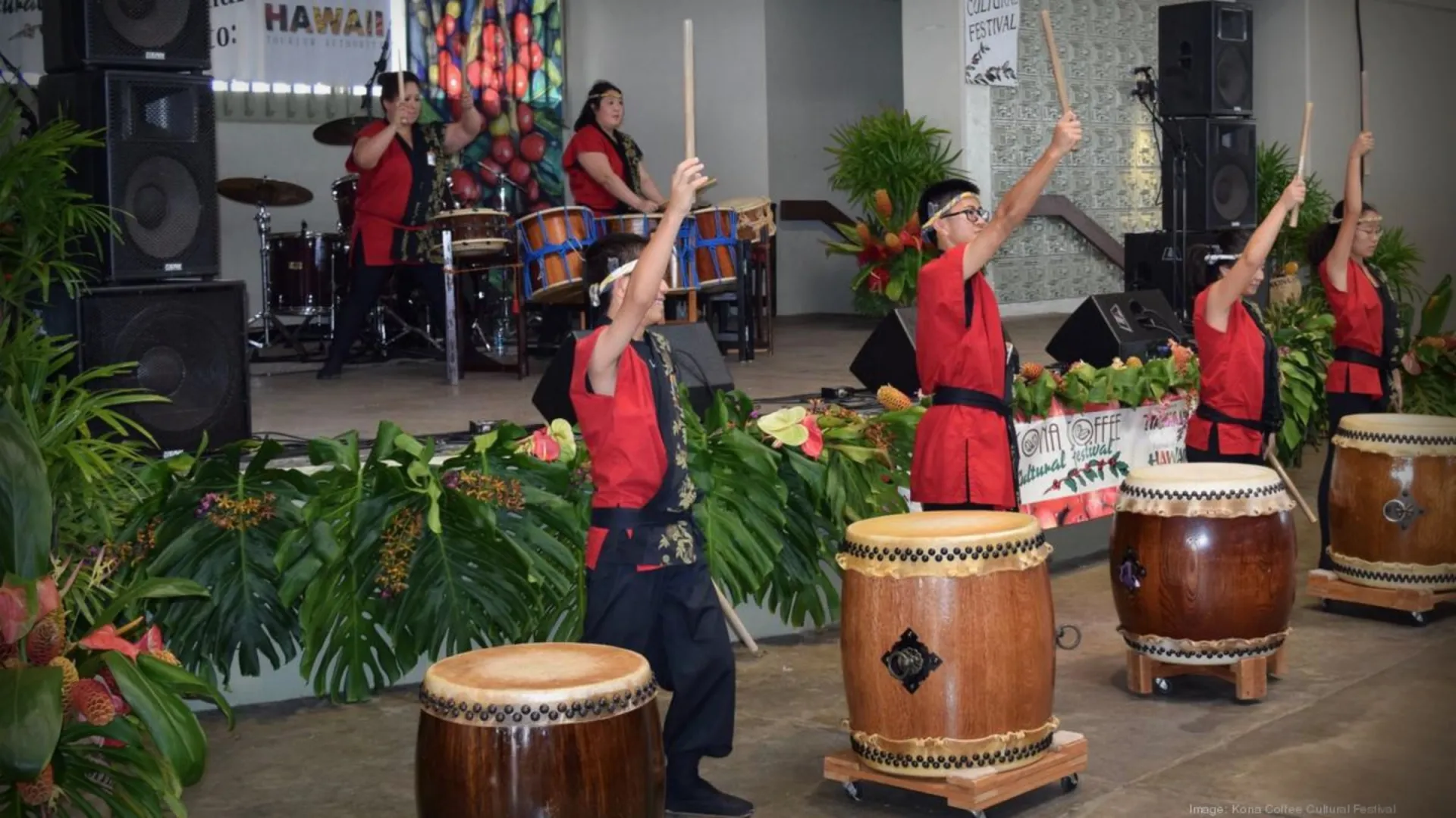 Taiko drummers in red and black outfits performing at a festival.